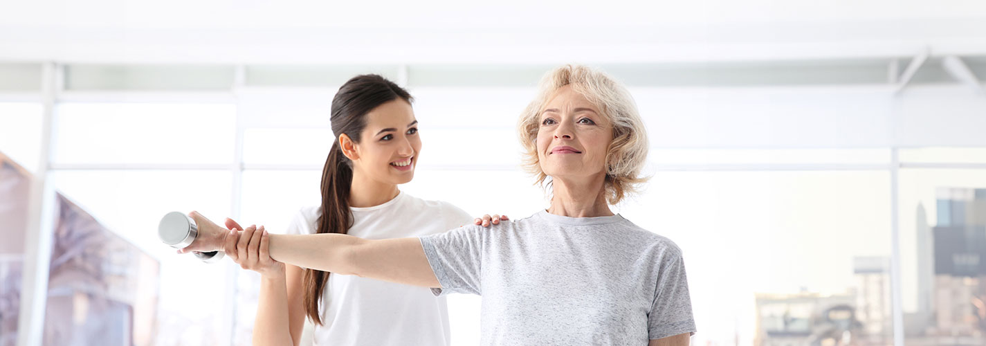 Physiotherapist works on range of motion exercises with an elderly patient in a bright modern clinic.