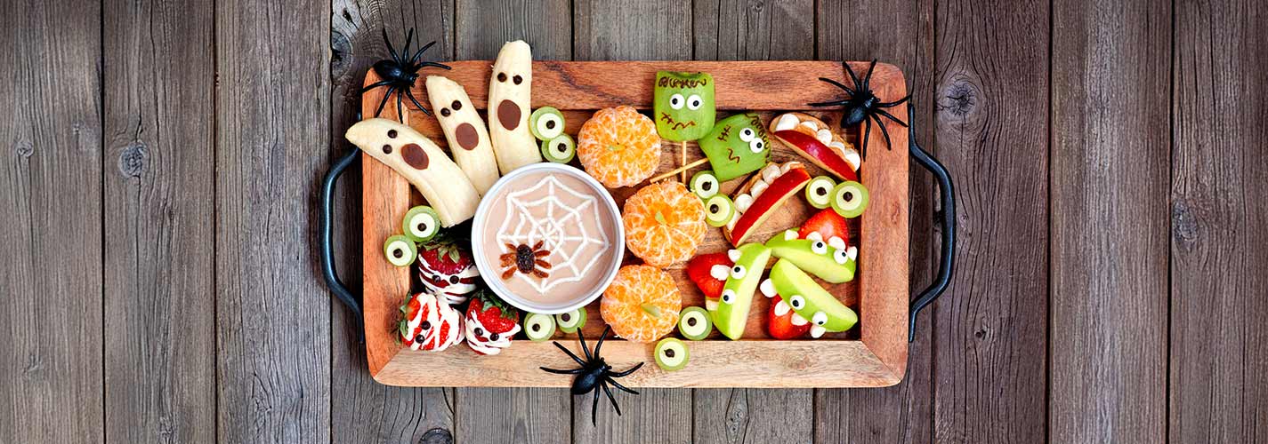 Top view, of a board of healthy fruit snacks decorated for Halloween.