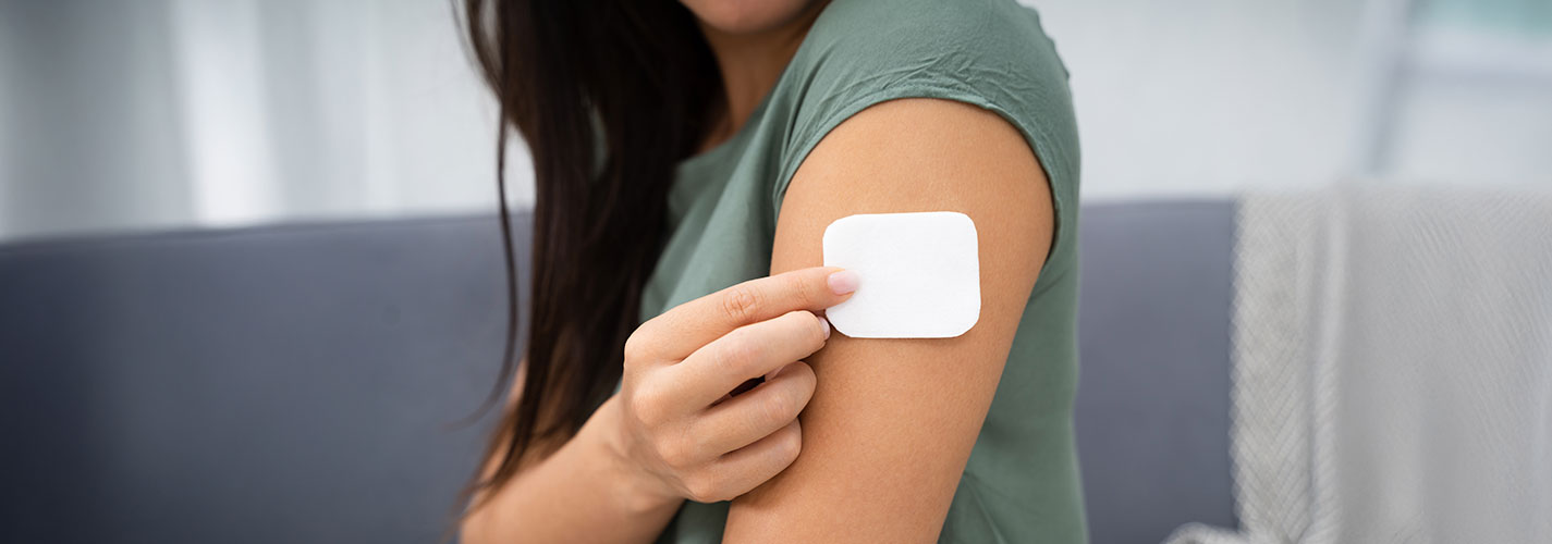 Woman applies a nicotine patch to her arm.