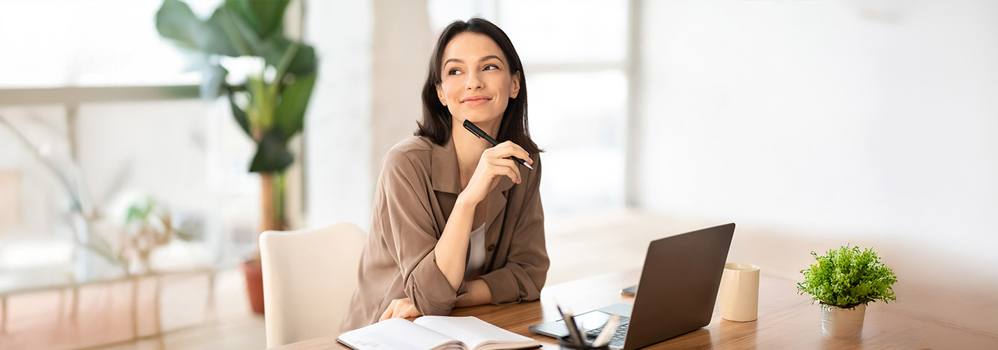 Smiling woman touching chin with pen looking to the side.