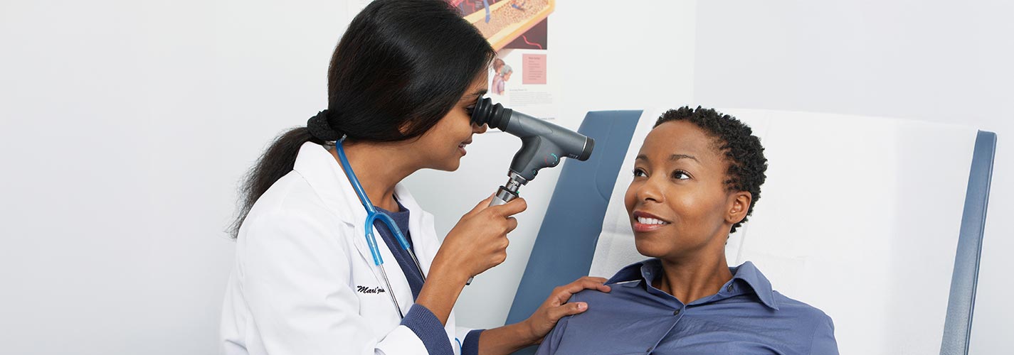 An African American woman has her eyes checked by her eye doctor.